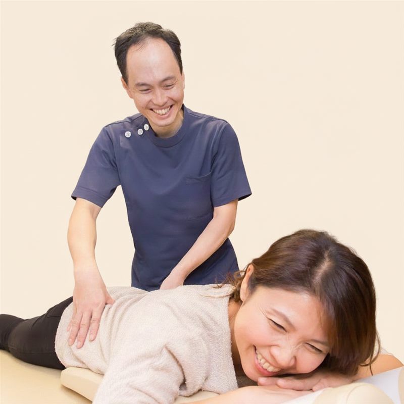 うつ伏せで施術を受けながら、院長と笑顔で話す女性患者